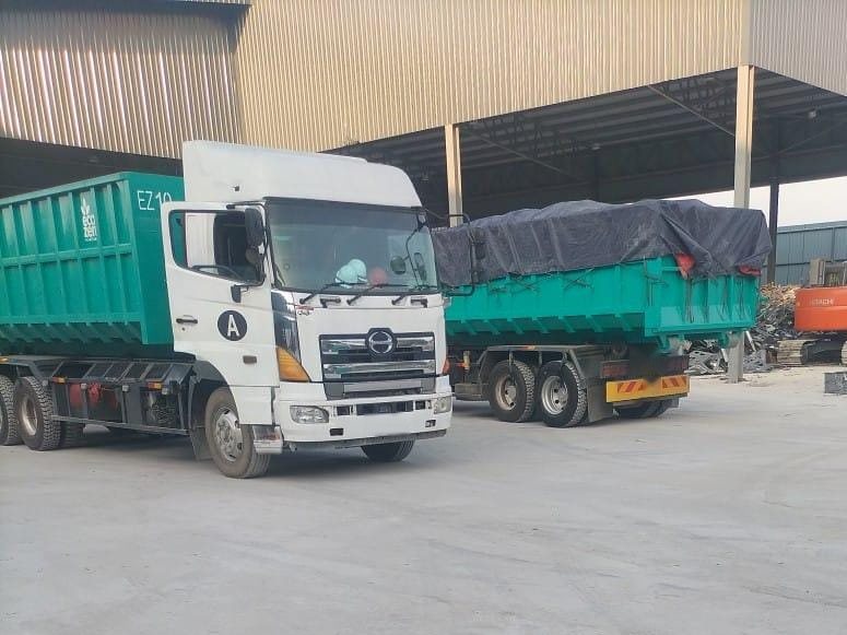 Two Eco Zen hook-lift lorries with roll-on roll-off bins at the yard