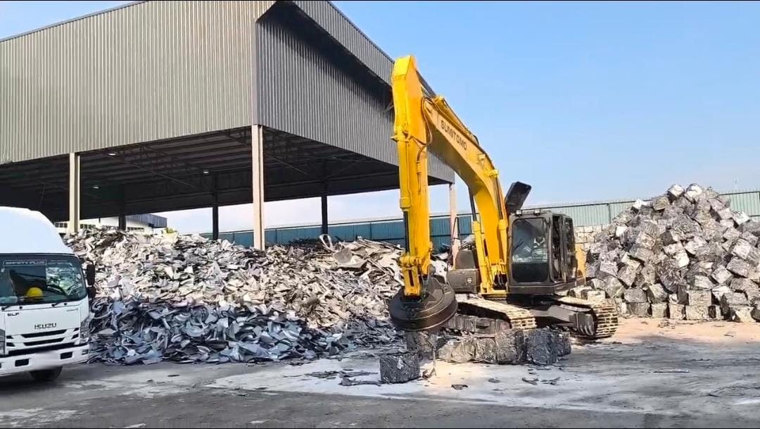 An excavator with a scrap magnet working a pile of scrap metal at the Eco Zen yard